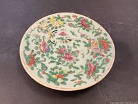 Top-down view of 7-inch celadon porcelain plate with colorful floral and bird designs.