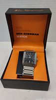 Ben Sherman wristwatch inside original orange and black branded box, showing watch face and band.