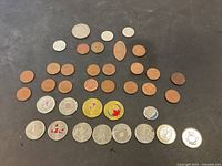 Overview of Canadian coins inclusive of pennies, commemorative quarters and loonies spread on black background.