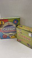 Two boxed items, the Cranium board game and Cadoo Booster box, sealed and in good condition.