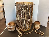 Front view of the drum and two hide rattles showing fur, braided ties, and leather details