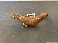 Side view of the polished brown stone seal carving with natural veining and carved flippers.