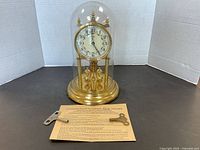 Full view of Kundo 400 Day clock under glass dome with two winding keys and original instructions.