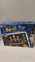 Box of Lite-Brite electric light-up picture maker toy showing colorful box with image of a birthday cake and child using the toy.
