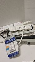 Photo showing six white power bars with multiple outlets and the Coby dual USB power adapter in packaging.