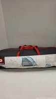 Front view of the black carry bag with the printed label illustrating the sun shelter and product details.
