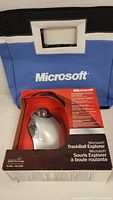 Microsoft Trackball Explorer original retail box and small Microsoft branded blue and black carry bag displayed together.