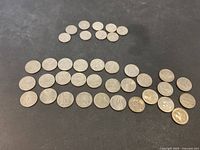 Image showing a group of US coins spread out on a dark surface. Larger coins appear to be commemorative quarters.