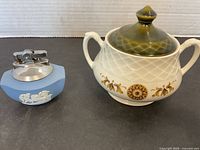 Blue Wedgwood jasperware lighter next to Wedgwood sugar bowl with lid on white background