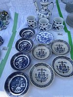 View of the entire set including tea pot, plates, and mugs arranged on a white surface, showing assortment of blue and white porcelain items.