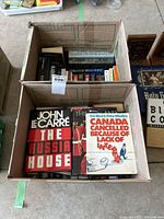 Photo of two boxes containing assorted books, including 'The Russia House' and 'Canada Cancelled Because of Lack of Interest'.