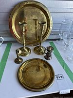 Overview of brass items showing candlestick holders, plates, candlestick, brass phone statue and sterling cup