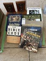 Photo showing variety of coffee table books and a pair of brown leather or faux leather University of Toronto bookends with embossed design.