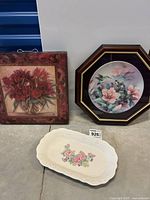 Overall lot showing framed floral canvas art, framed limited edition decorative plate, and floral ceramic oval plate on the floor