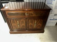 Front angled view of the wooden sideboard showing drawer and cupboard doors with brass handles and veneer inlay