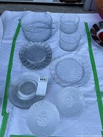 Overview of glass bowls, salad utensils, and serving plates arranged on a white surface with green tape borders