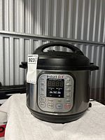 Front view showing overall Instant Pot unit with handle, lid, and stainless steel body.