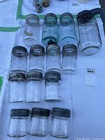 Top view of all 14 Mason jars arranged on white cloth, showing different sizes and metal lids, mostly embossed Crown logo visible