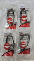Lot of four Jackson V40 HellRaiser safety glasses in sealed packaging, arranged in two rows of two on a plain surface, showing full lot and packaging condition.