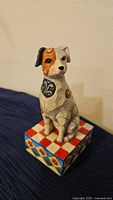 Full view of ceramic terrier dog figurine decorated with hearts and paws, sitting on a checkered patterned base.