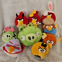 Full lot of 9 Angry Birds plush toys together on a gray textured surface, showing various characters including birds and pigs.