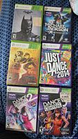 Seven Xbox 360 game cases showing front covers including Batman: Arkham City, Michael Jackson The Experience, Resident Evil 5, Just Dance 2014, Dance Central 2, Dance Central