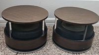 Two round MCM Zenith Circle Of Sound speakers showing wood top and base with metal supports and mesh grille center.