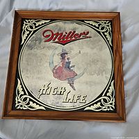 Full view of the square Miller High Life advertising mirror showing wooden frame and entire mirrored image with girl on crescent moon, brand text, and decorative border.