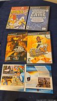 Photo of 4 PlayStation 2 game cases and 2 opened game manuals laid out on a flat surface.
