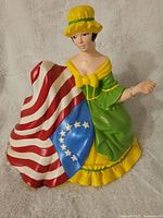 Front view of the hand painted ceramic Betsy Ross figurine, showing seated figure holding a 13-star American flag.
