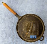 Top view of 10" cast iron skillet with wooden handle and matching lid on top, showing surface wear and rust.