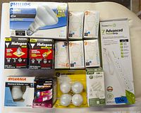 Photo showing all items in original packaging including various Philips, Sylvania, and TCP lightbulbs and a TrickleStar seven-outlet power strip