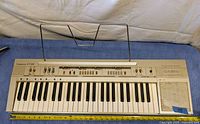 Full view of the Casiotone CT-310 keyboard showing the entire key set, controls, speaker, and sheet music stand.