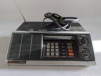 Front view of Bearcat 210 XL CB radio showing keypad, speaker, knobs, and antenna bent at base.