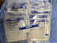 Top view of all fourteen sealed packs of clear face shield covers stacked in two rows.
