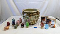 Full lot view showing ceramic planter, 11 assorted decorative eggs, and two boxed tealight candle sets