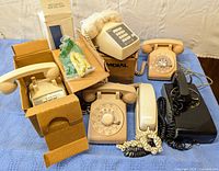 Full view of all six telephones, some boxed, showing different models and colors including black wall phone, beige rotary dials, and boxed phones.