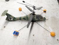 Top perspective of the lightweight RC army helicopter showing rotor blades, orange tipped landing rods, and camo paint.