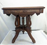 Front view of Victorian walnut end table showing carved legs and wooden frame.