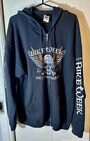 Front view of black zip-up hoodie with skull and wing graphic and text 'Bike Week 2018 Daytona Beach'
