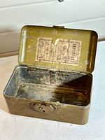 Open view of interior showing metal construction and original paper sticker on lid