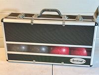 Closed black and silver textured Sportcraft carrying case with clear window showing red and black bocce balls inside.
