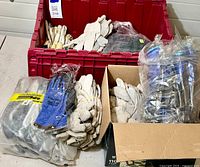 Boxes filled with multiple pairs of work gloves, some still in plastic packaging and others in bundles.