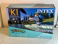 Box front showing Intex Challenger K1 one-person sit-in kayak with image of person paddling on water.