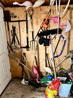 View of entire garden shed wall with multiple hanging garden tools and decorative flamingos.