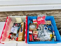 Two large bins filled with various car parts and accessories. Visible are branded boxes and loose parts including a steering wheel horn ring and small packaged parts.