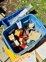 Blue plastic bin filled with assorted Ford Thunderbird car parts and related items, some boxed, some loose.