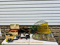 Wide shot showing rolling tackle bag, landing net, lures organizer, two tackle boxes, reels and rod on table