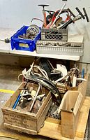 Four crates of assorted bicycle parts on a table including chainrings, forks, handlebars and small components