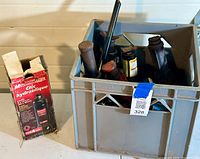 Milk crate containing multiple black metal jack stands and related items.